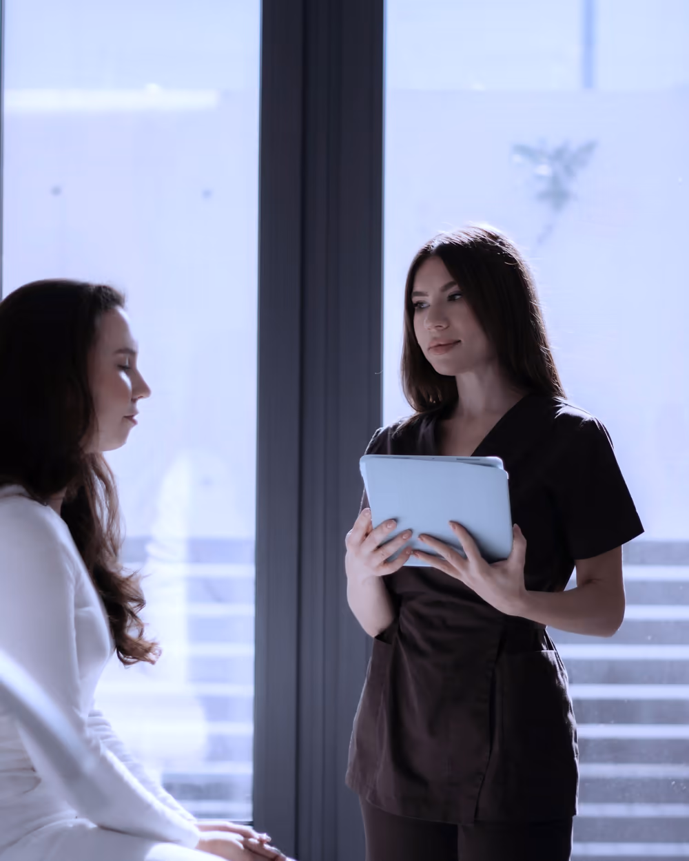 A consultation at Marin Aesthetics: a provider reviewing a treatment plan on a tablet with a client in natural light